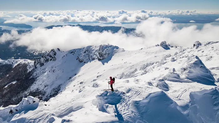 Rider on a wind-scoured ridge above the clouds