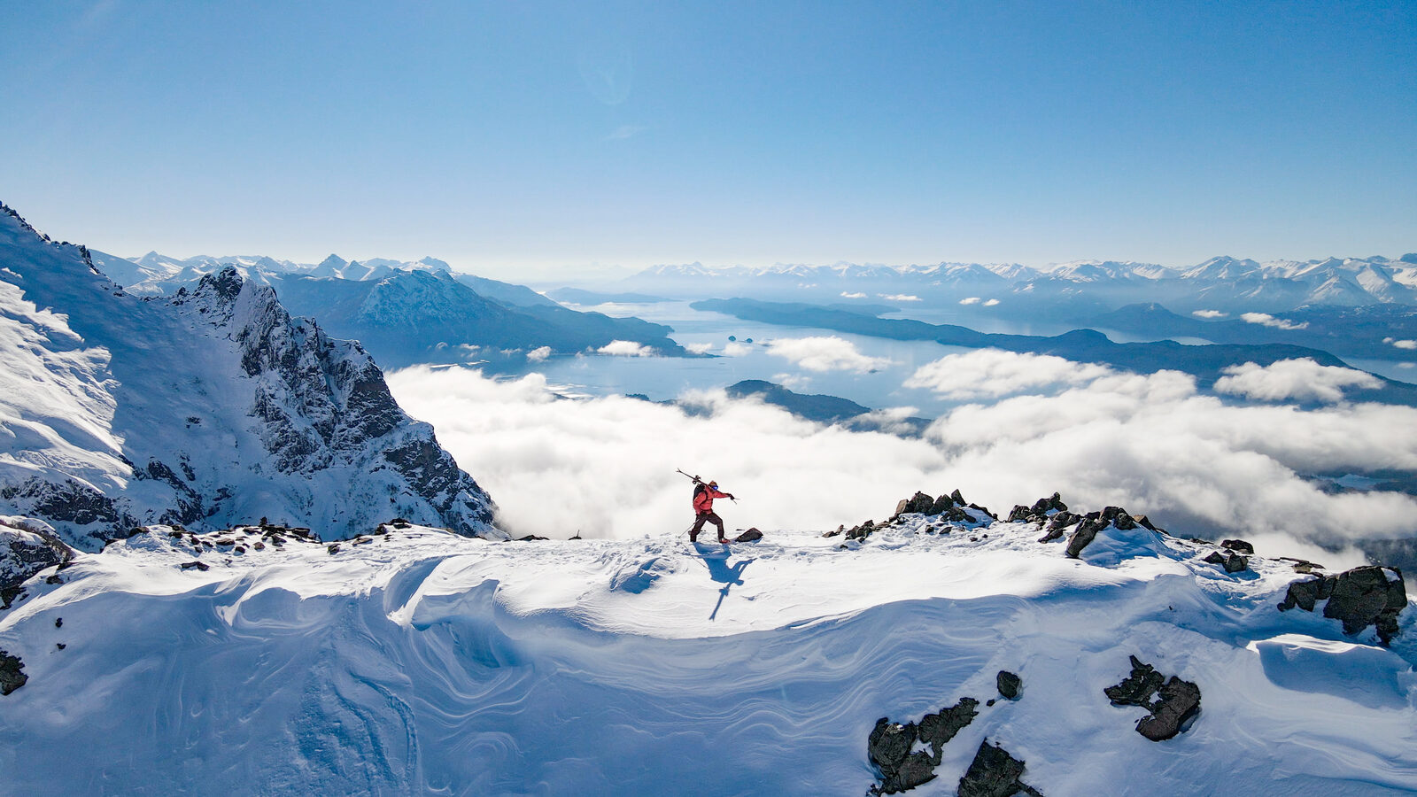 Rider standing on wind-sculpted snow above the clouds at Cerro Catedral, Bariloche